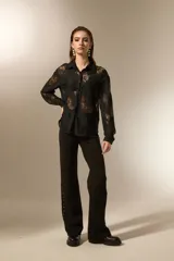 Camisa negra de poliamida con diseño calado de encaje floral, corte holgado, cuello camisero, botones frontales y mangas largas.