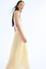Pollera larga color amarillo pálido, de gasa plisada, con cintura alta con elástico fino y forro interior.
