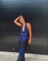 Vestido largo de fiesta con estampado floral en tonos azul y negro, escote halter y espalda descubierta.