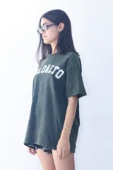 Remera oversize color verde oliva con estampado frontal de texto en blanco.
