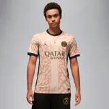 Camiseta de fútbol Nike del Paris Saint-Germain, modelo Stadium Fourth temporada 2023/24, para hombre. Diseño color chocolate con estampado de camuflaje y detalles en azul marino en cuello y mangas. Incluye logo de Nike, escudo del club y sponsor Qatar Airways en el frente.