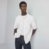 Camisa blanca de manga corta con cuello clásico y cierre abotonado.
