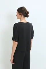 Conjunto de pijama negro, compuesto por una remera de manga corta con detalle de encaje en los puños y un pantalón largo de corte recto.