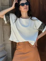 Remera negra de corte holgado con mangas cortas con volados y detalle de apliques de piedras en los volados.