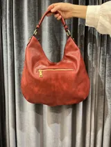Cartera hobo grande color ladrillo con diseño tejido.