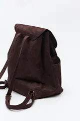 Mochila negra de símil gamuza con textura tipo reptil, diseño minimalista con solapa, cordón ajustable y bolsillos laterales.
