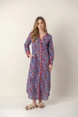 Vestido largo con estampado floral en tonos rosa y verde sobre fondo blanco. Tiene cuello con volantes, cierre frontal con botones y mangas largas con puños elásticos.