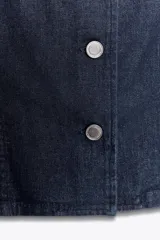 Chaleco de denim azul oscuro, sin mangas, con cuello redondo y cierre frontal con botones metálicos.