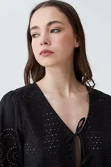 Blusa color crudo de broderie con escote en V y cierre frontal con lazos.