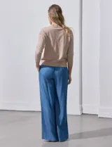 Cárdigan color beige tejido en hilado fino, con escote en V y cierre frontal con un botón.