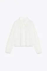 Camisa blanca de manga larga con cuello solapa y bordados perforados a tono. Cierre frontal con botones.