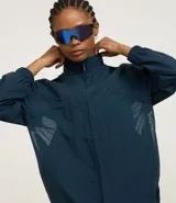 Campera deportiva tipo cortavientos en color azul petróleo, con cuello alto y cierre frontal completo. Presenta recortes de tul translúcido en los laterales, puños elásticos y bolsillos funcionales. Confeccionada en tejido de poliamida.