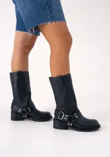 Bota de cuero marrón oscuro con caña media, estribo desmontable y hebilla metálica. Taco de madera de 5cm y suela de caucho.