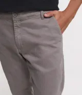 Pantalón de vestir marrón, de corte skinny, con bolsillos laterales y traseros. Se ajusta a la cintura con cinturón de cuero marrón.
