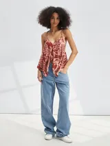 Musculosa con estampado abstracto en tonos rosados y marrones, con breteles finos y corte asimétrico.