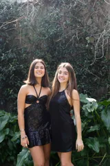 Vestido corto de lentejuelas color ciruela o morado oscuro, con escote corazón y detalle de argolla central que conecta con tirantes finos que atan al cuello. Presenta aberturas laterales (cut-outs) en la zona de la cintura y falda corta con vuelo.