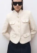 Chaqueta de tweed color crudo con cuello mao, cuatro bolsillos delanteros con solapa y botones dorados.