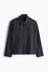 Campera gris oscuro de sarga con cuello clásico, cierre frontal con cremallera, bolsillos laterales insertados al bies, puños con botón a presión y forro interior.