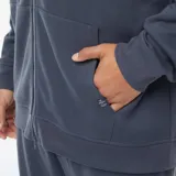 Buzo azul de piqué con cierre de cremallera frontal, capucha con cordones ajustables y bolsillos laterales.