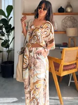 Pantalón palazzo de satén con estampado de cadenas en tonos beige, marrón y blanco. Tiene cintura elástica.