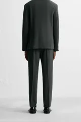 Pantalón de vestir azul marino, de corte slim fit, con bolsillos laterales y traseros. Se ajusta a la cintura con cinturón de cuero marrón.