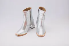 Botas plateadas de cuero con caña media, cierre lateral con cremallera y tacón geométrico.