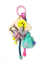 Llavero con dije de tela con carita sonriente, estrella de peluche gris, borla de hilo turquesa y cordones de colores.
