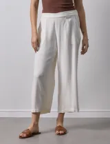 Pantalón de lino color crudo, de corte ancho y tiro alto, con bolsillos laterales y cintura elástica.