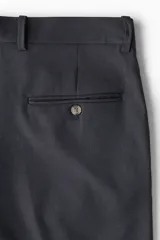 Pantalón de vestir negro de corte recto, con bolsillos laterales y traseros. Se ajusta a la cintura con cinturón.