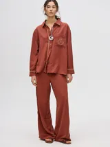 Pantalón de vestir color ladrillo, de corte holgado y tiro alto, con caída recta y detalle de diseño al costado.