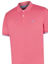 Chomba de piqué color rosa con cuello clásico y tapeta de dos botones. Tiene mangas cortas con puños acanalados con detalles de líneas blancas y azules. Presenta un logo bordado en el pecho.