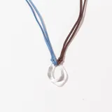 Collar con colgante de vidrio transparente en forma de gota irregular, con cordón doble de gamuza sintética color celeste y marrón.
