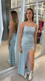 Vestido largo de fiesta celeste con brillos, breteles finos y espalda cruzada. Tiene tajo en la pierna izquierda y corte ajustado en la cintura.