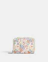 Billetera de cuerina con estampado floral multicolor, bolsillo frontal y cierre circundante con tirador metálico.