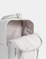 Mochila negra de tela deportiva con correas regulables, manijas superiores con broche, acceso con cierre superior y puller de cuerina, bolsillo frontal con cierre y puller de cuerina, y tag de goma.