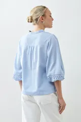 Blusa celeste con escote en V y bordado floral en el frente y en las mangas 3/4.