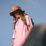 Sombrero tipo bucket hat de color mostaza, confeccionado en tela ripstop con protección UV, secado rápido y repelente al agua. Presenta una cinta decorativa con presillas en la corona y cordón ajustable con tanca para la barbilla. Lleva bordado el nombre "Martha" en blanco.