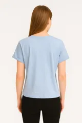 Remera celeste de manga corta y cuello redondo, con estampado de sardinas sobre fondo a cuadros rojos y blancos. Incluye texto con los nombres de las ciudades de Cagliari y Sardina.