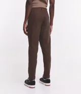 Pantalón de vestir marrón, de corte skinny, con bolsillos laterales y traseros. Se ajusta a la cintura con cinturón de cuero marrón.