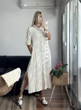 Vestido camisero midi color crudo con bordado floral, cuello camisero, mangas 3/4 con trabilla y abertura lateral. Incluye cinturón de soga con hebilla de madera.