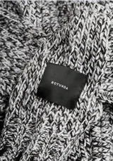Cardigan de punto grueso color gris jaspeado, con cuello alto y mangas largas.