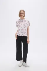 Remera blanca con estampado floral en color lila, de corte holgado y mangas cortas.