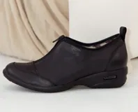 Zapato bajo de cuero negro con cierre de cremallera frontal.