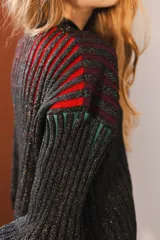 Cárdigan tejido con lurex, con cuello redondo, manga 3/4 y cierre frontal con botones forrados. Diseño con rayas verticales en tonos verde, azul y violeta sobre fondo negro con brillo.