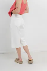 Bermuda de tiro medio color crema, con corte recto y largo a la rodilla. Diseño amplio tipo culotte corto, con dobladillo ancho en el ruedo. Presenta bolsillos delanteros y traseros funcionales.