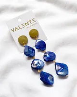 Caravanas de estilo festivo con piedras azules en forma irregular y detalles dorados.