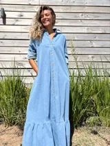 Vestido camisero largo de jean celeste con botones frontales, cuello camisero y volado en el ruedo.