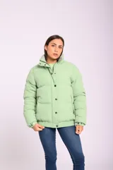 Campera puffer acolchada color verde claro, con cuello alto, cierre con botones a presión y bolsillos laterales con cierre.