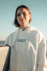 Hoodie color natural con estampado en la espalda con la frase "Glassy Waves" y dibujos de palmeras, labios y tablas de surf.