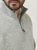 Buzo polar color gris jaspeado, con cuello alto, medio cierre frontal y bolsillos laterales. Confeccionado con fibras de poliéster reciclado.
